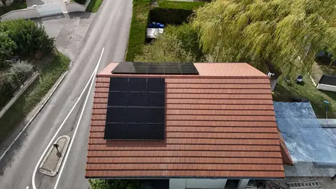 Panneaux photovoltaïques noirs posés sur une toiture en tuiles à Maubec (38), vue depuis la rue