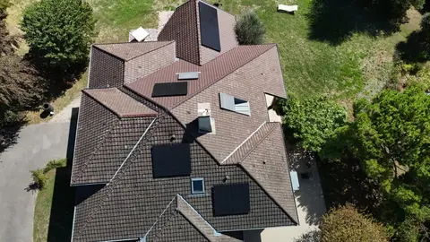 Vue aérienne d'une maison à Maubec (38) avec panneaux photovoltaïques répartis sur plusieurs pans de toiture en tuiles